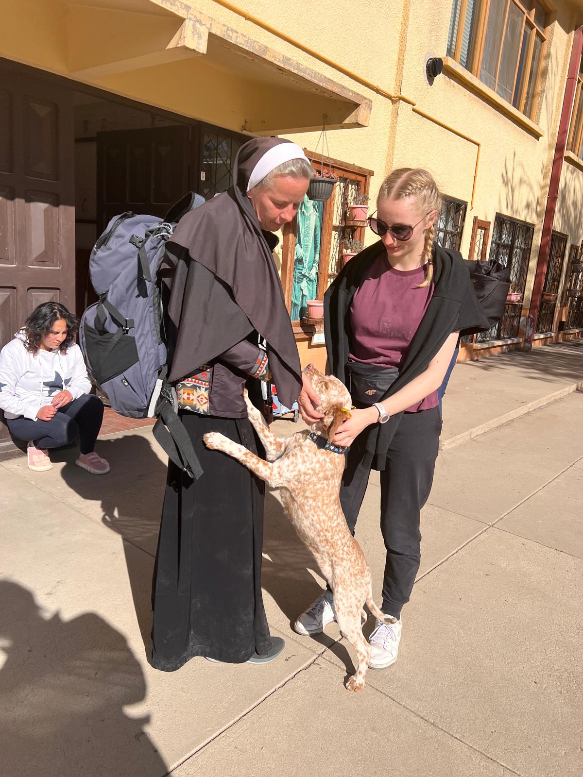 Od prawej Weronika Tietz obok siostra zakonna głaskają psa na ulicy.