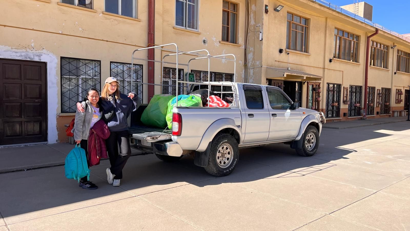 Od prawej Zuzanna Krzywda obok niej Boliwijka przy samochodzie na ulicy w tle budynki