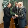 fotografa postaci stojących: od lewej ks. prof. dr. hab. Paweł Zając OMI, prof. dr hab. Mariusz Wołos, prof. dr hab. Jan K. Ostrowski wręczający nagrodę