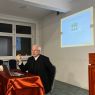 ks. prof. UAM dr hab. Maciej Olczyk siedząc przy stole przemawia do słuchaczy