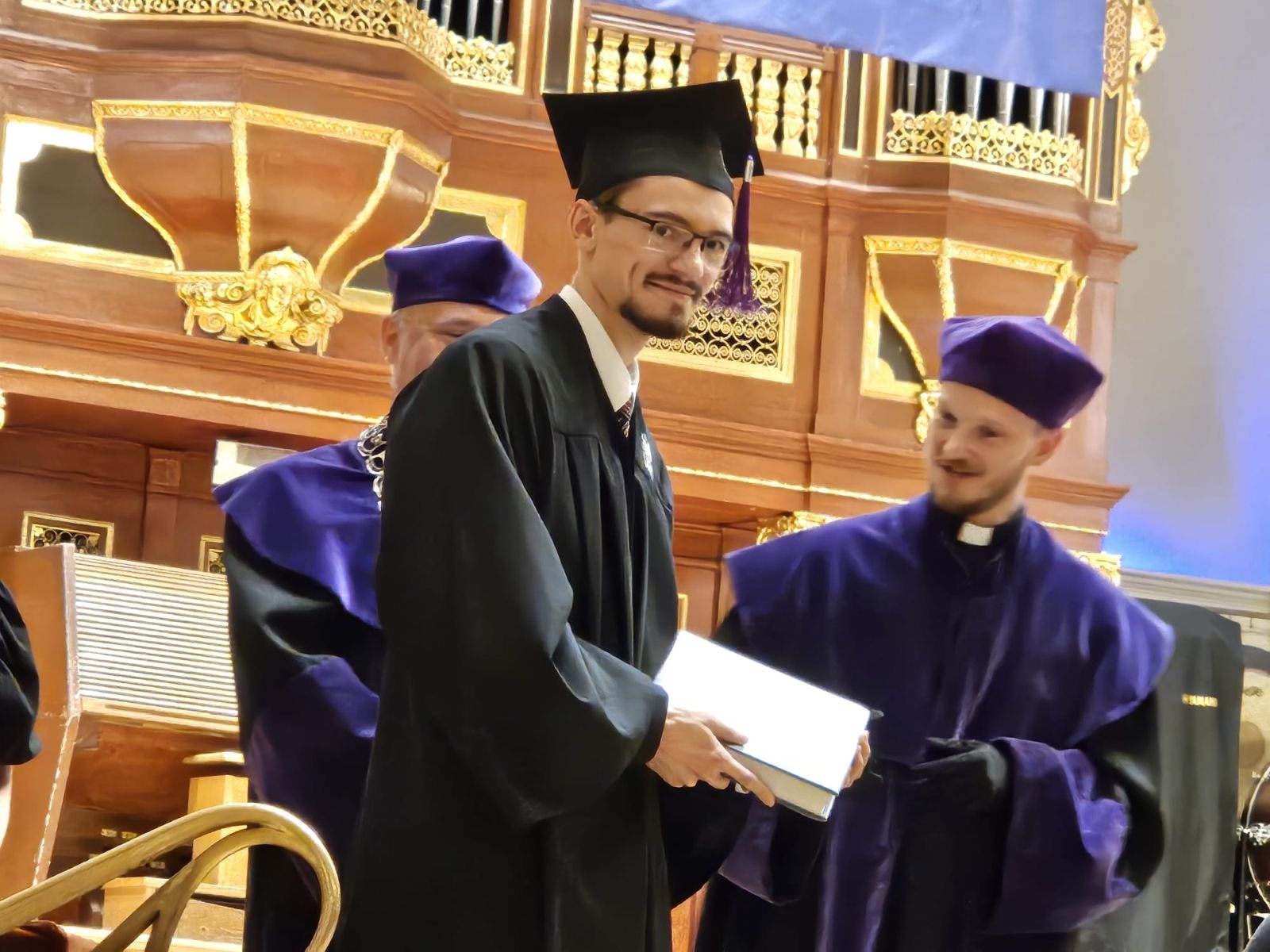 na pierwszym planie Marcin Fuchs oraz ks. dr Przemysław Zgórecki za nimi ks. prof. UAM dr hab. Mieczysław Polak