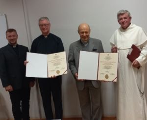 od lewej strony stojące postacie: ks. prof. UAM dr hab. Tomasz Nawracała, o. prof. UAM dr hab. Adam Wojtczak OMI, ks. prof. dr hab. Jan Daniel Szczurek, o. prof. Andrzej Napiórkowski