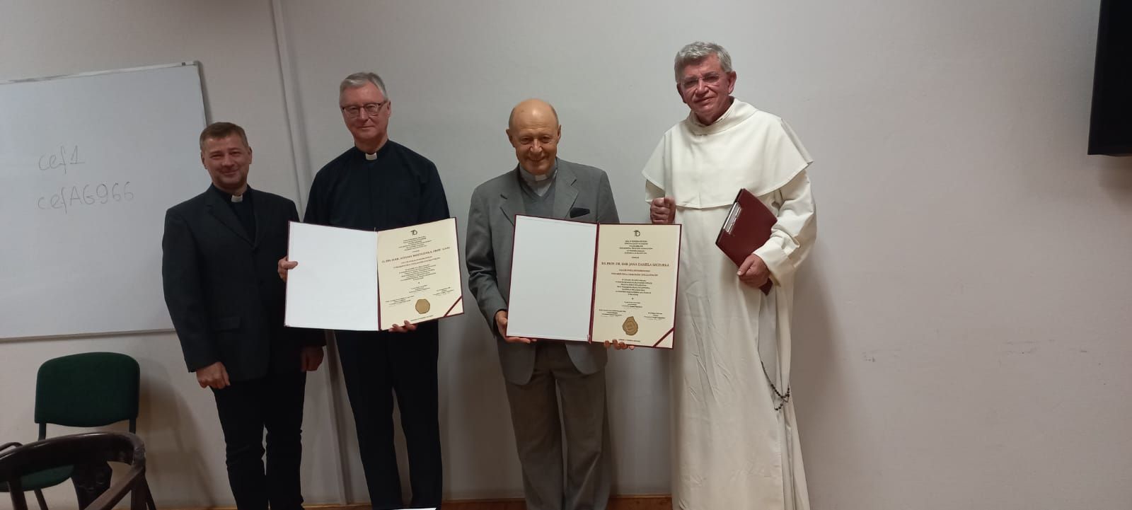 od lewej strony stojące postacie: ks. prof. UAM dr hab. Tomasz Nawracała, o. prof. UAM dr hab. Adam Wojtczak OMI, ks. prof. dr hab. Jan Daniel Szczurek, o. prof. Andrzej Napiórkowski