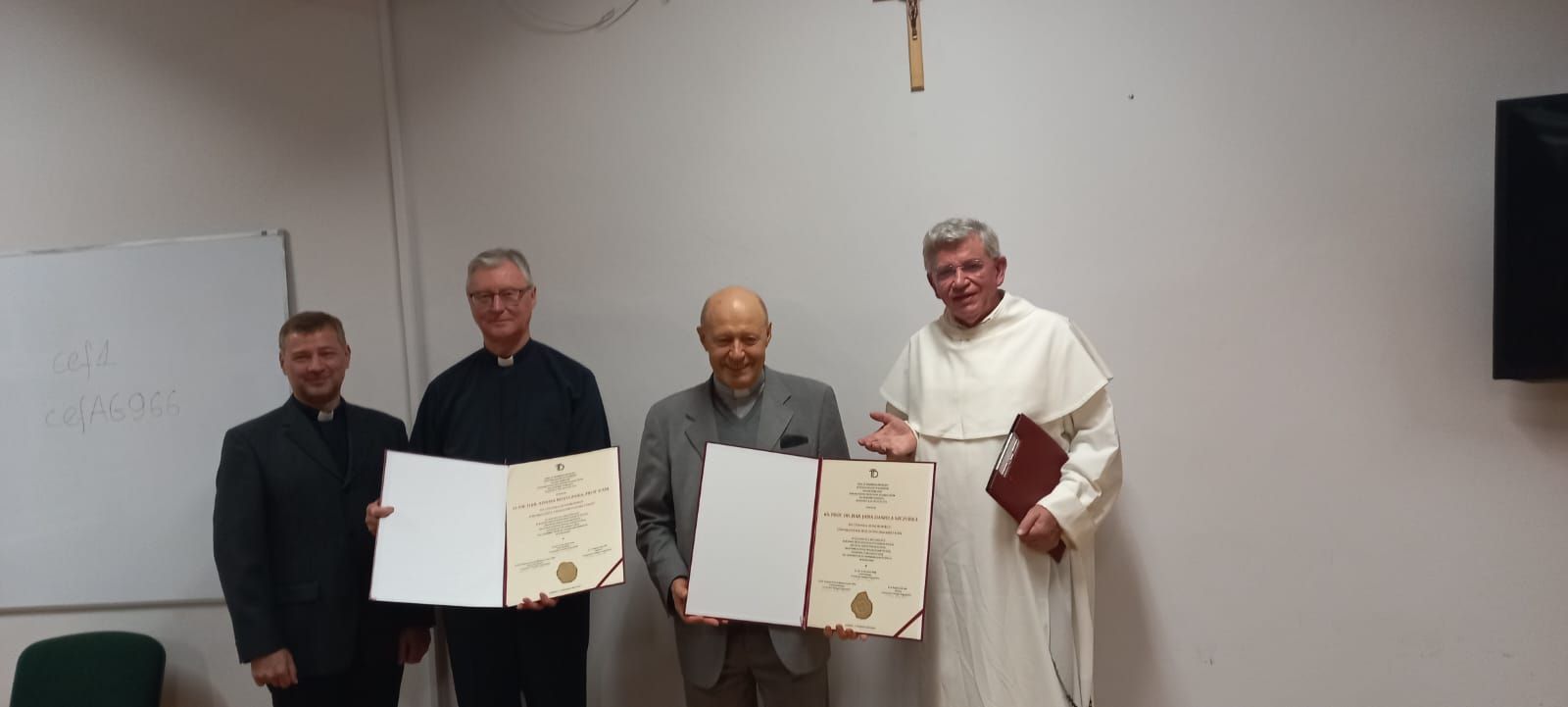 od lewej strony stojące postacie: ks. prof. UAM dr hab. Tomasz Nawracała, o. prof. UAM dr hab. Adam Wojtczak OMI, ks. prof. dr hab. Jan Daniel Szczurek, o. prof. Andrzej Napiórkowski